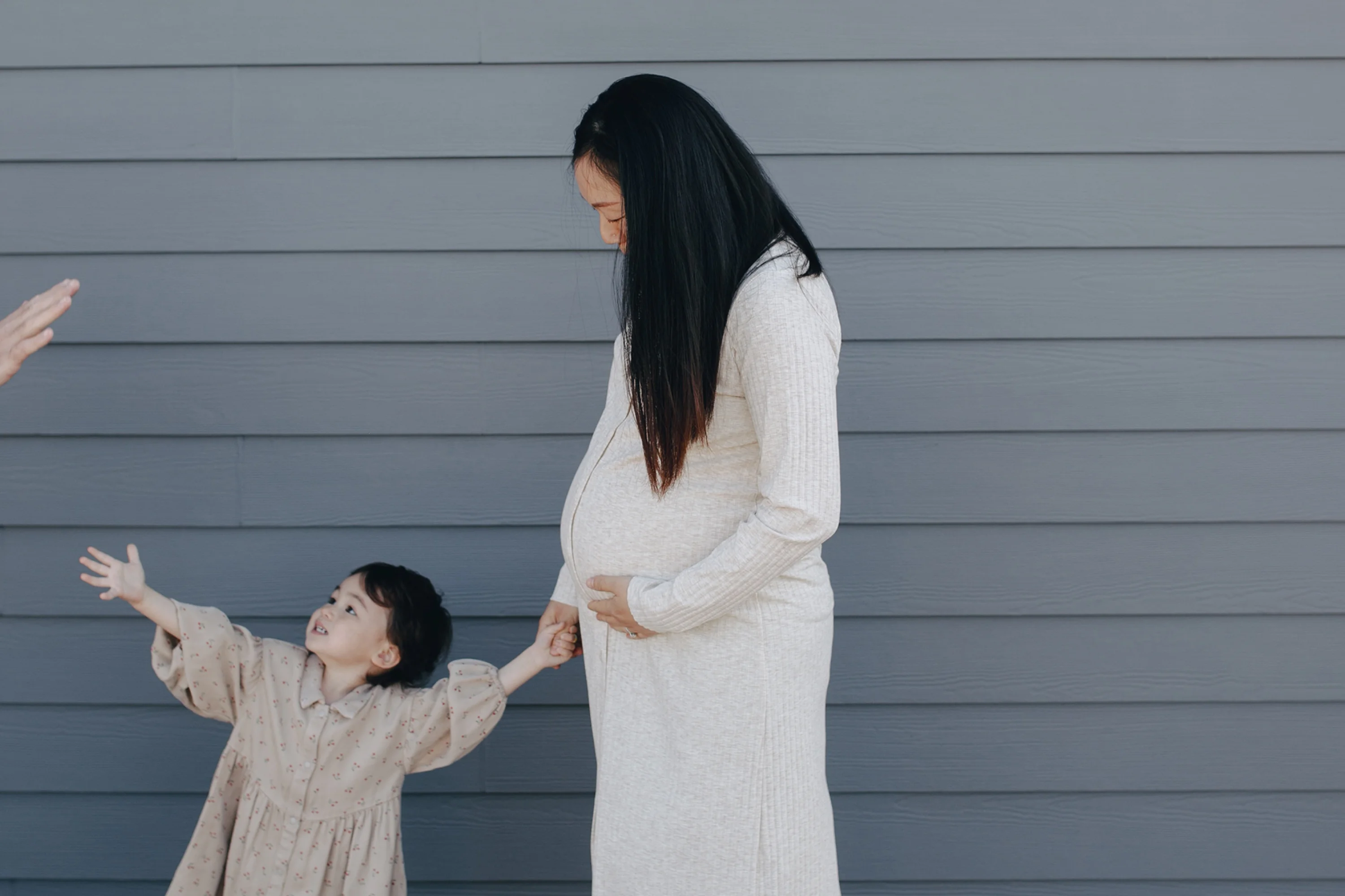 a pregnant women holding hands with her young child